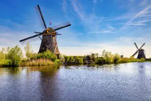 View from the canal, the shore showing two windmills and one in the background in perspective. Kinderdijk, Netherlands.