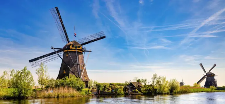 View from the canal, the shore showing two windmills and one in the background in perspective. Kinderdijk, Netherlands.